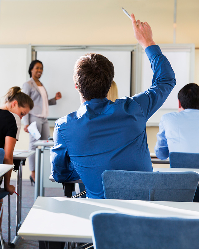 Business student raising their hand in a classroom