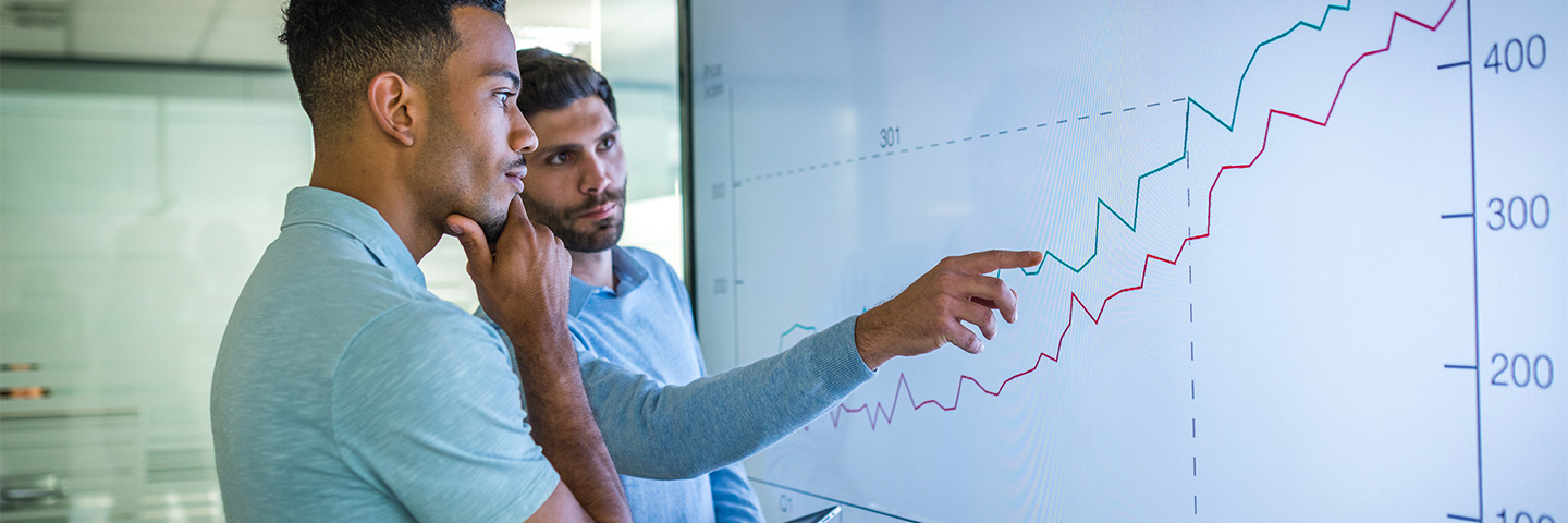 Two business people looking at financials on a monitor