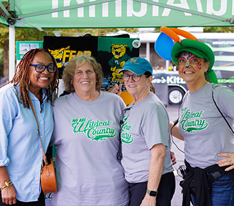 Four WilmU employees smiling while wearing WilmU festive gear.