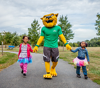 WilmU mascot Wiley walking with children.