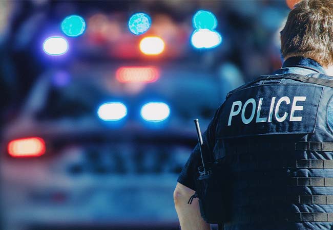 Police officer standing in front of police car.