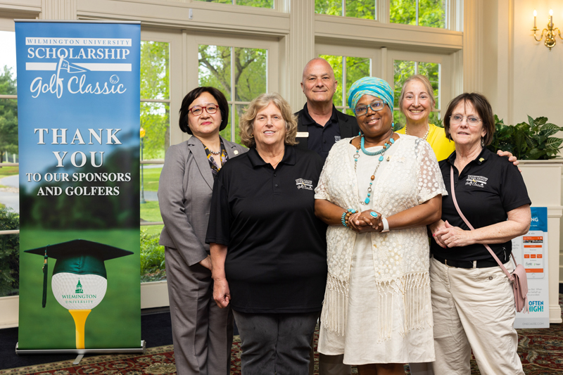 Six people at the golf scholarship event standing and smiling