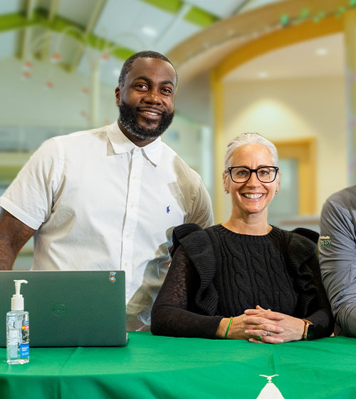 Two staff members smiling on WilmU campus.
