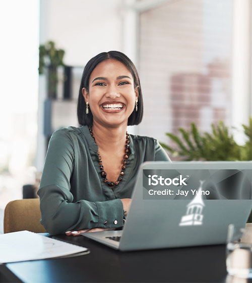 WilmU employee smiling at computer.