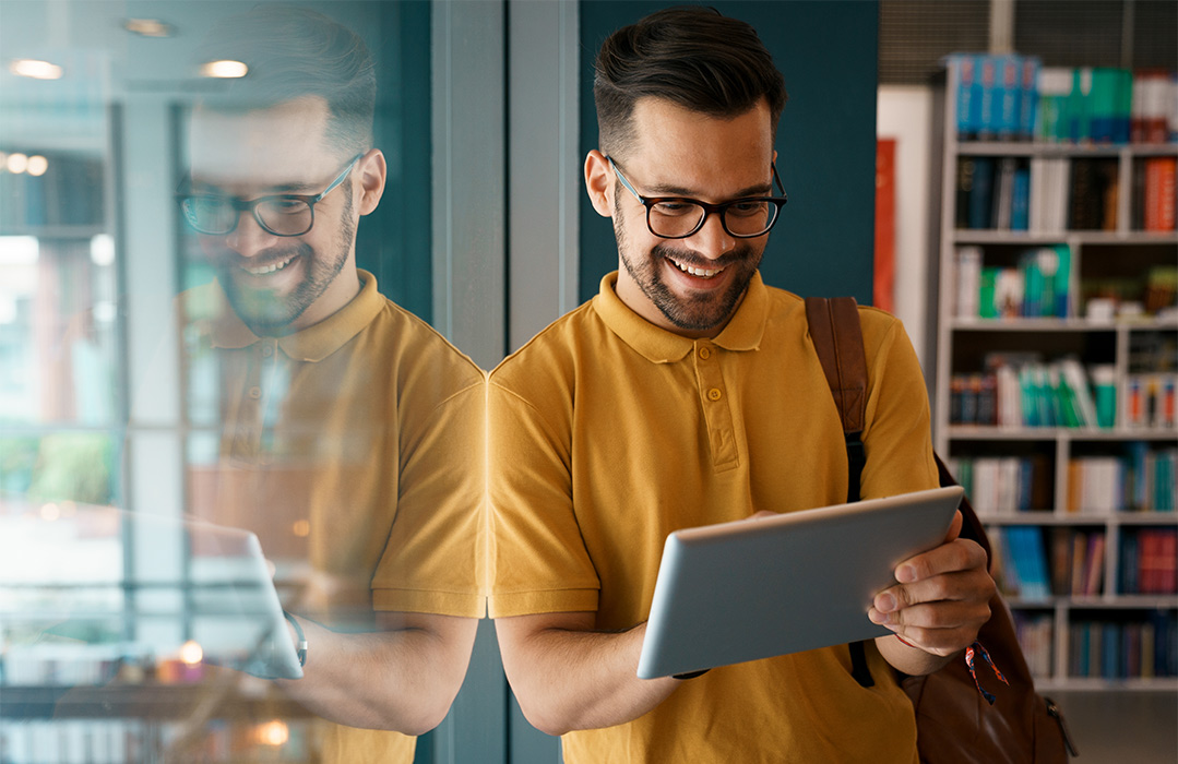 man sitting next to a window on the computer smiling