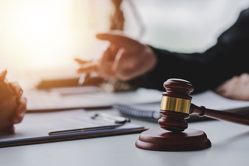 Two people sitting, hands showing, with a gavel in between