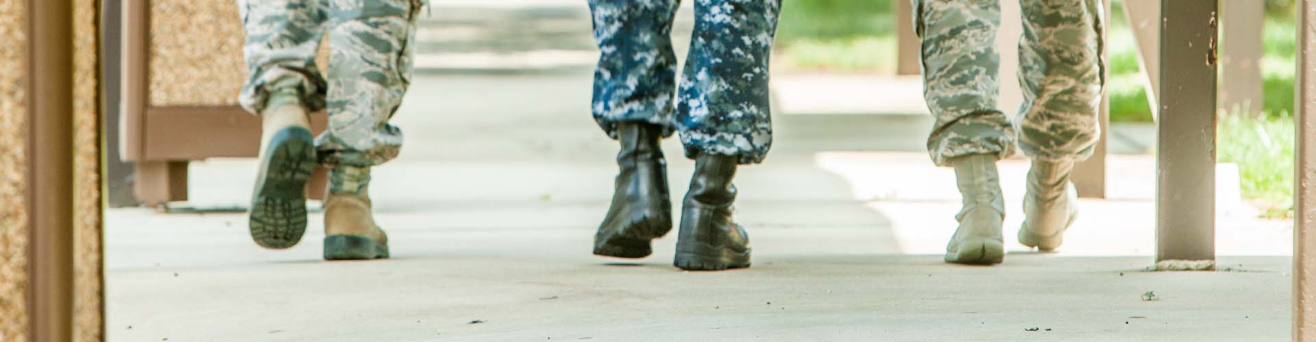 Close-up of 3 military personnel boots as they walk away.