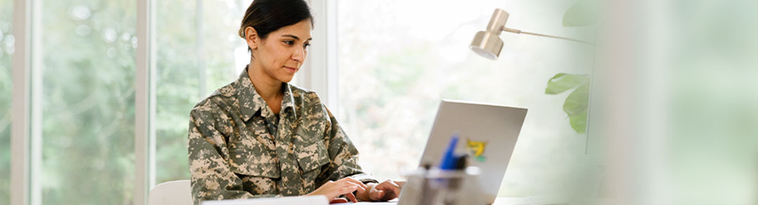 Service woman in fatigues working on laptop
