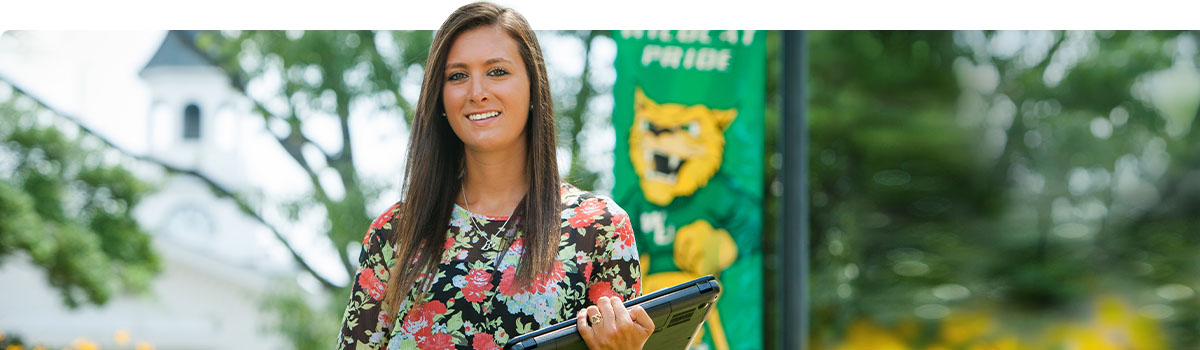 Female student walking on campus with a laptop.