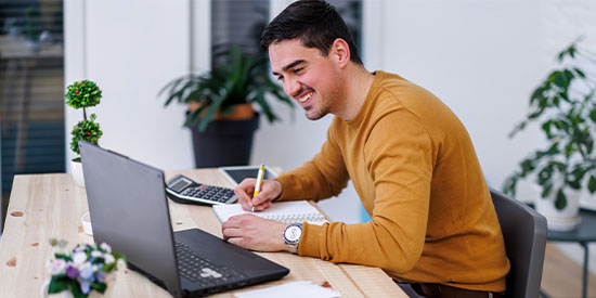 Male student working at desk on laptop.