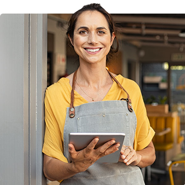 Woman with yellow shirt smiling at the camera holding an ipad