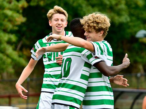 Three teammates celebrating while playing soccer