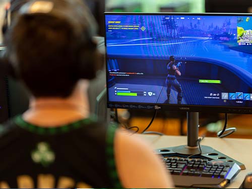 Student sitting at desk with a computer competing in a game