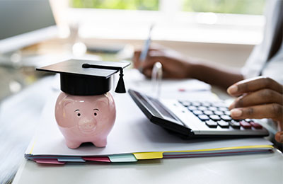 Piggy bank sitting in front of laptop on a desk.