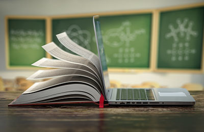 Book pages blowing open on a desk in a classroom.