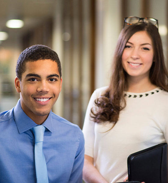 Two people standing and smiling while wearing business attire