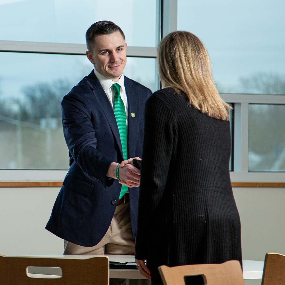 a picture of a University staff member greeting a student