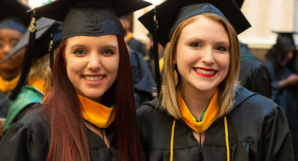 Two students dressed in graduation cap and gown